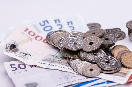 En vifte af danske pengesedler med en bunke mønter ovenpå. 